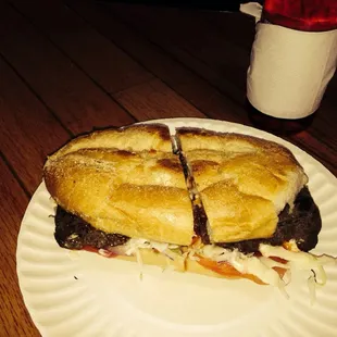 a half eaten sandwich on a paper plate