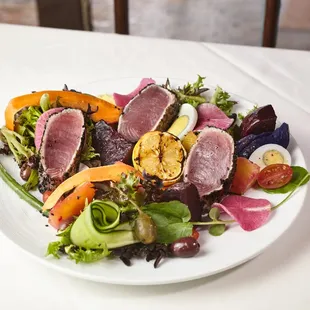 Niçoise Salad  Sesame crusted tuna, mixed greens, green beans, hardboiled egg, tomatoes carrots, caperberries, kalamata olives.