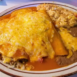 3 soft tacos with red sauce served with beans and rice.