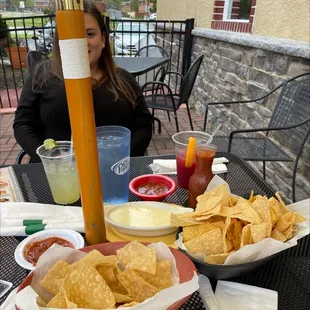 a woman sitting at a table with chips and drinks