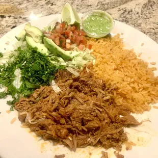 Shredded pork with Mexican rice. Along with some lettuce, cilantro, avocado, pico de gallo, lime and avocado sauce.