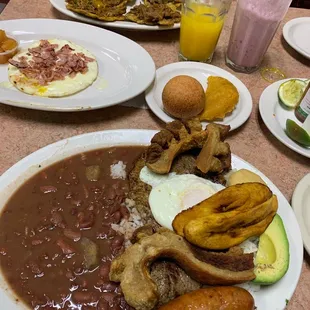 Tostone con Carne Desmechada, Jugo de Agua, Jugo de Leche, Arepa Hawaiana, Buñuelo, Empanada, y Bandeja Paisa