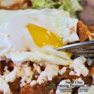 Chilaquiles Santa Cruz with egg - Fried corn tortilla pieces cooked in red chili, mixed with tomato, white onion and Monterrey cheese.