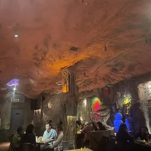 people sitting at tables in a cave like setting