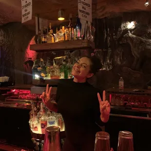 a woman making a peace sign at a bar