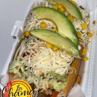 a hot dog with avocado