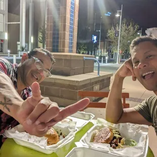 two men sitting at a table with food