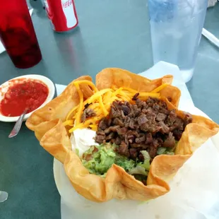 a taco bowl with meat, cheese, and guacamole