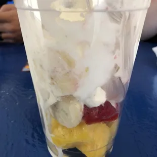 a plastic cup filled with ice cream and fruit