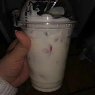 a hand holding a plastic cup of milk