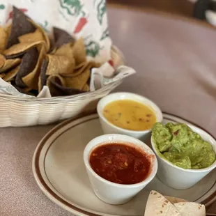a plate of chips, guacamole and salsa