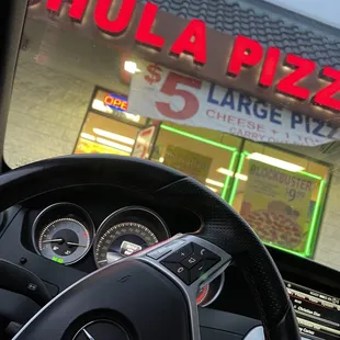 a steering wheel in front of a pizza shop
