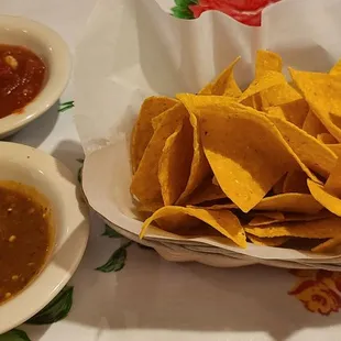 a bowl of tortilla and two bowls of salsa