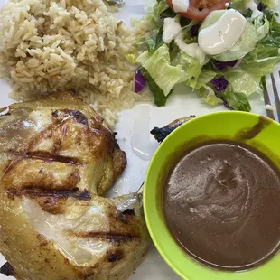 Plato de pollo asado con arroz, frijoles y ensalada
