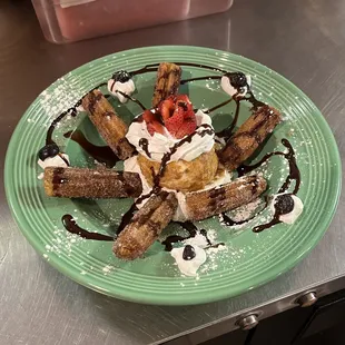 a plate of waffles with whipped cream and strawberries