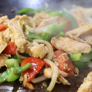 chicken and vegetables cooking in a wok