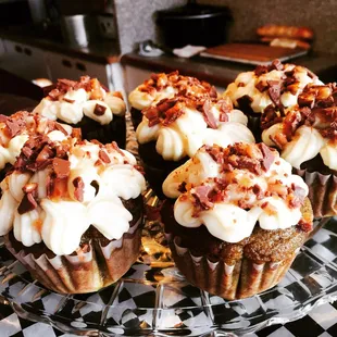 a plate of cupcakes with bacon and cream frosting