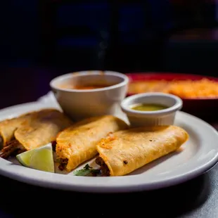 a plate of burritos and a bowl of salsa