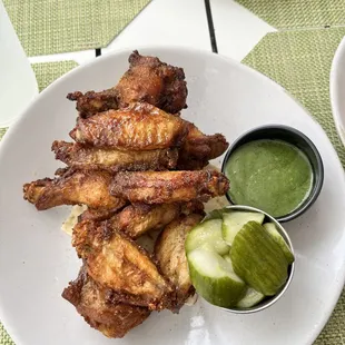 a plate of chicken wings with a side of pickles