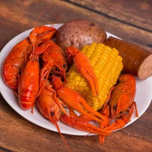 a plate of lobster, corn and potatoes