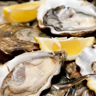 a pile of oysters with lemon wedges