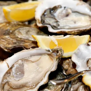 a pile of oysters with lemon wedges