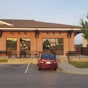 a red car parked in front of a restaurant