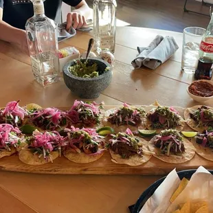 a long wooden table topped with tacos