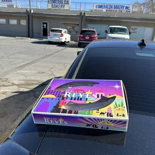 a pizza box on the hood of a car