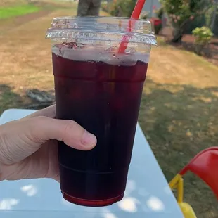 a hand holding a plastic cup with a straw