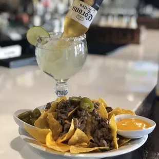 a plate of nachos and a bottle of beer