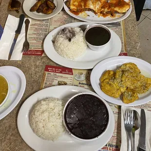 Two sides of white rice, one small and one medium black beans, garlic tostones, maduros, and bistec a la milanesa.