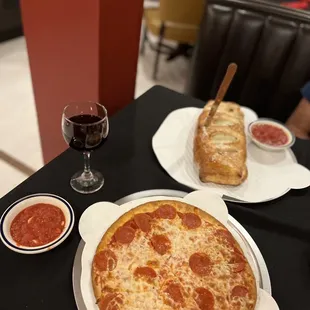 a pepperoni pizza and a glass of red wine