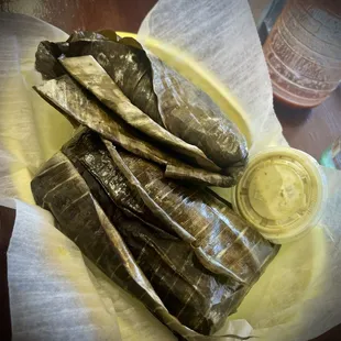 Two wrapped pork tamales with verde sauce