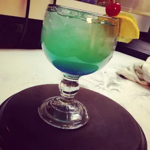 a blue and green drink with a cherry on top