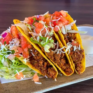 three tacos on a wooden platter