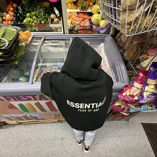 a person in a black hoodie standing in front of a refrigerated refrigerator