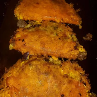 three enchiladas on a black plate