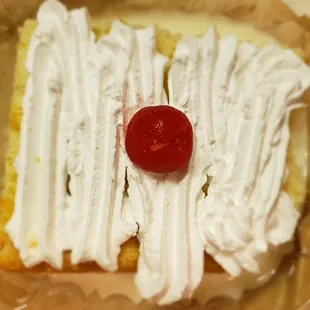 a piece of cake with whipped cream and a cherry