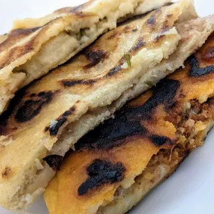 Loroco and cheese, revueltas, and chorizo and cheese pupusas, cut in half.