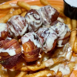 a plate of french fries and bacon wrapped in cheese