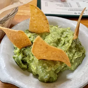 a bowl of guacamole and tortillas