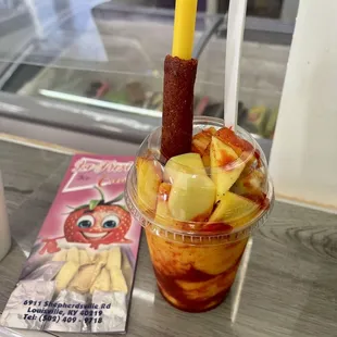 a cup of fruit with a stick sticking out of it