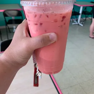 a hand holding a pink drink