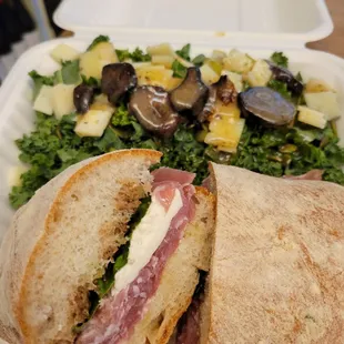 a sandwich and salad in a styrofoam container