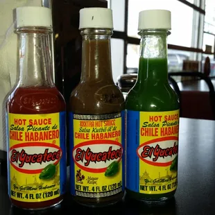 three bottles of hot sauce on a table