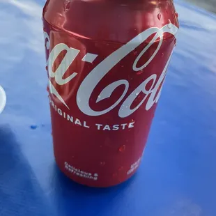 a can of coca cola on a blue table