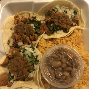 Al pastor street tacos with Mexican rice and a side of beans.
