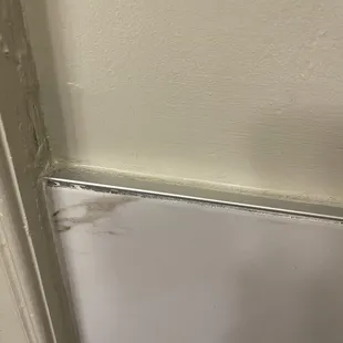 Edging where the wall and marble meet next to door - dust, dirt and grime not cleaned off