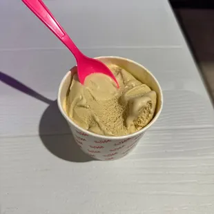 a cup of ice cream with a pink spoon